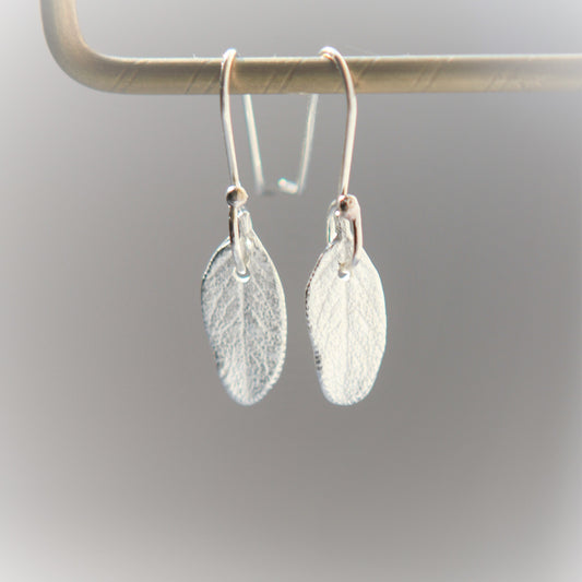 Earrings in the shape of a small sage leaf approximately 15mm long and 7mm wide made of pure silver. They have the texture and shape of a real sage leaf.  Each earring has a small hole at the top where the sterling silver ear wire attaches.  The ear wires are hand made and come with a complimentary plastic safety stopper that prevents loss.