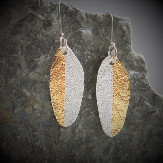Earrings with the shape and texture of a sage leaf approximately 32mm long and 13mm wide made of pure silver with 24K Gold accents.  Each earring has a small hole at the top where the sterling silver ear wire attaches.  The ear wires are hand made and come with a complimentary plastic safety stopper that prevents loss.