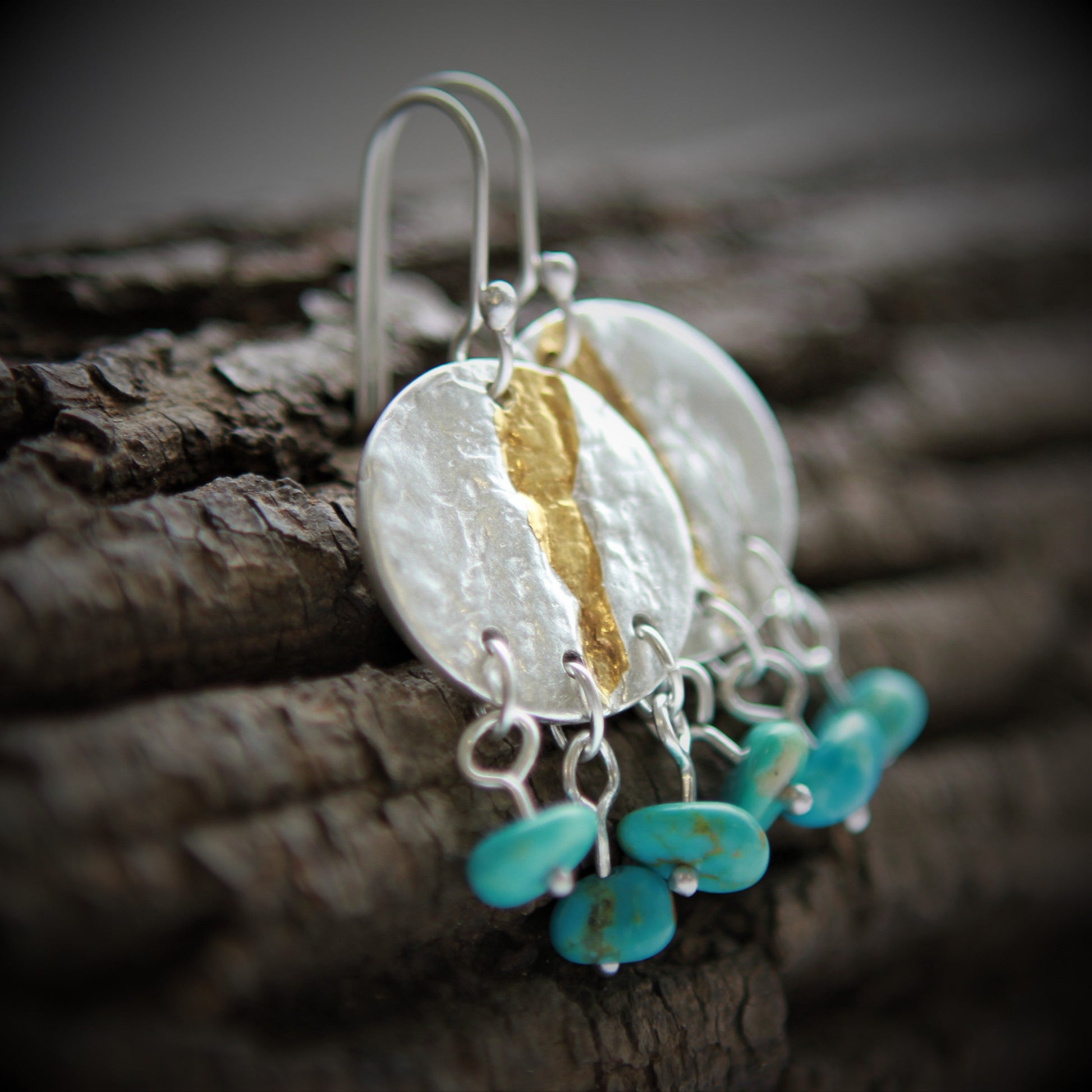 Circular earrings approximately the size of a quarter impressed with a maple bark texture in pure silver with a vein of 24K gold running through the the earring from top to bottom. 3 small natural turquoise beads are suspended individually from the bottom.  Sterling silver ear wires.  Earrings are matte finished.